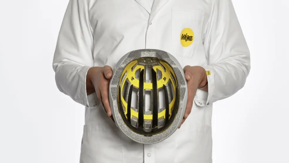 Person in white coat holding a helmet with yellow interior design.